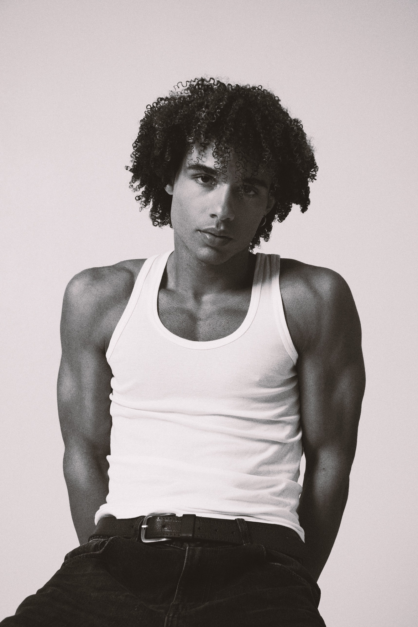 Black and white studio portrait of João in a white tank top