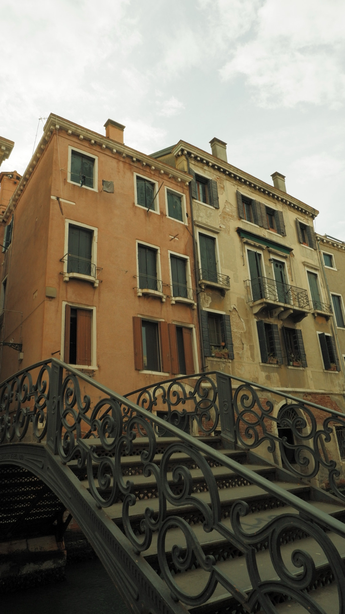 An ornate iron bridge in front of weathered facades