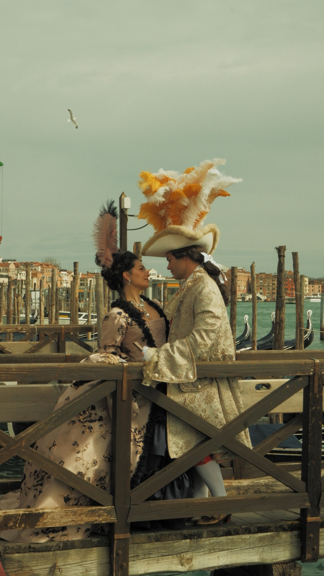 A couple in carnival costume with a feathered tricorn on a wooden jetty